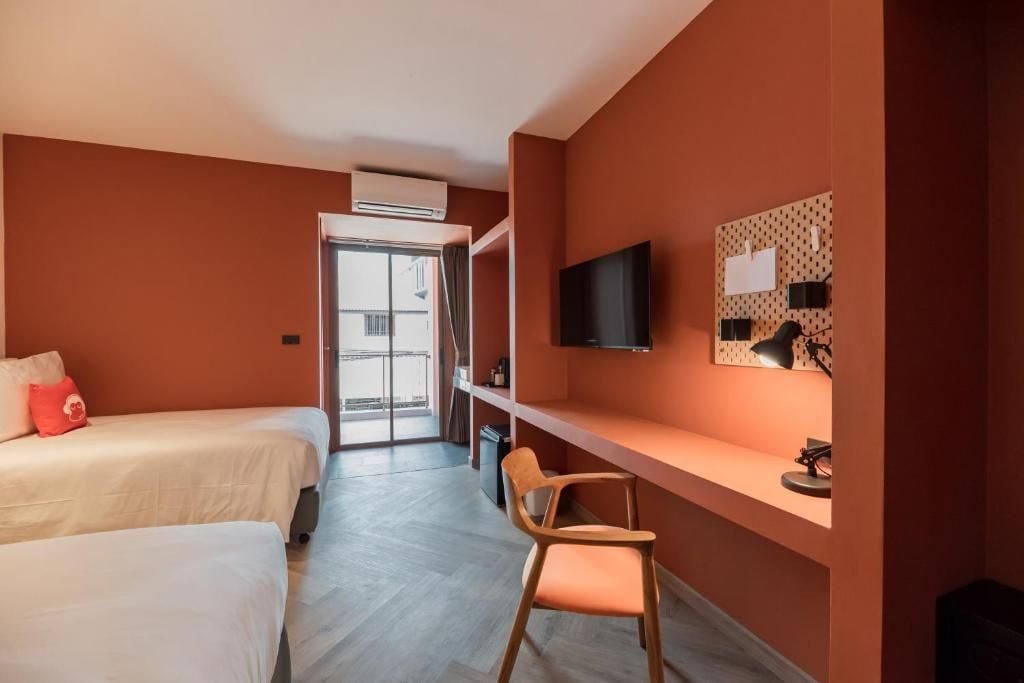 Een hotelkamer met twee bedden, een bureau, een stoel, een televisie en een raam met uitzicht.