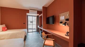 A hotel room with two beds, a desk, a chair, a TV, and a window with a view.