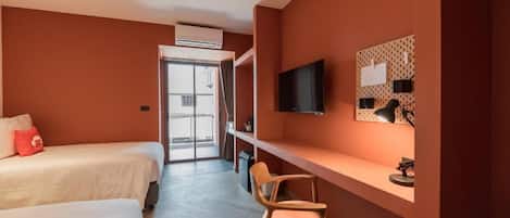 Habitación de hotel con dos camas, un escritorio, una silla, un televisor y una ventana con vistas.