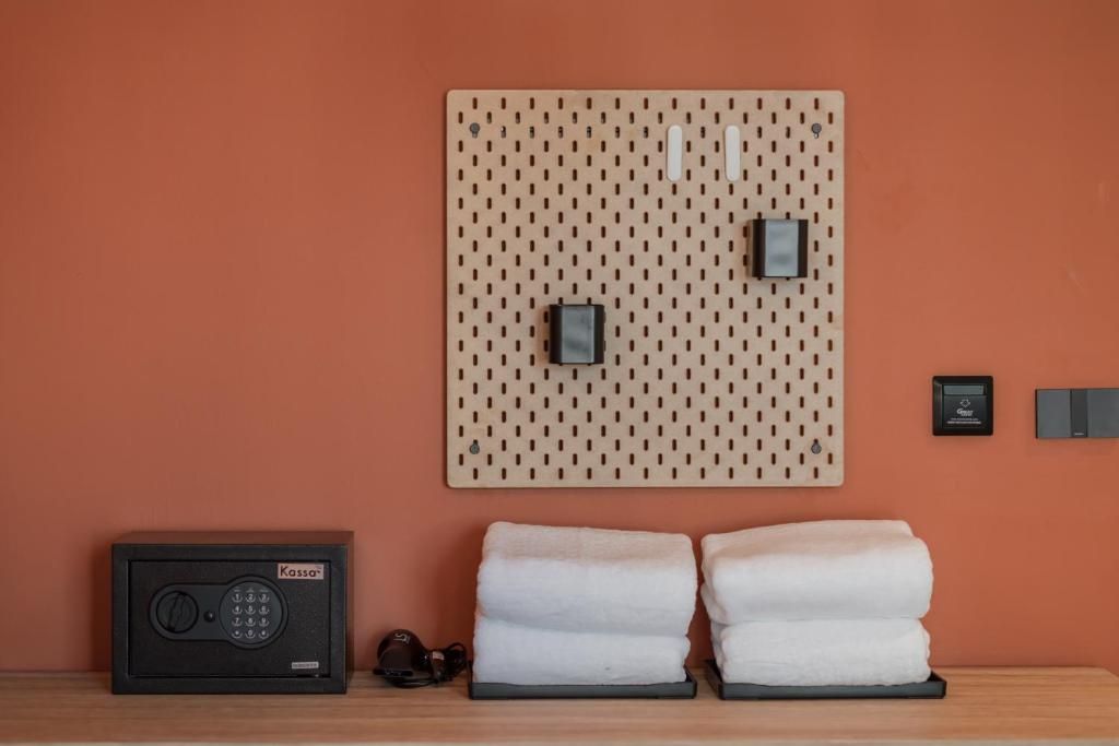 A wall-mounted pegboard with hooks and a small electronic device, a radio, and towels on a wooden surface.