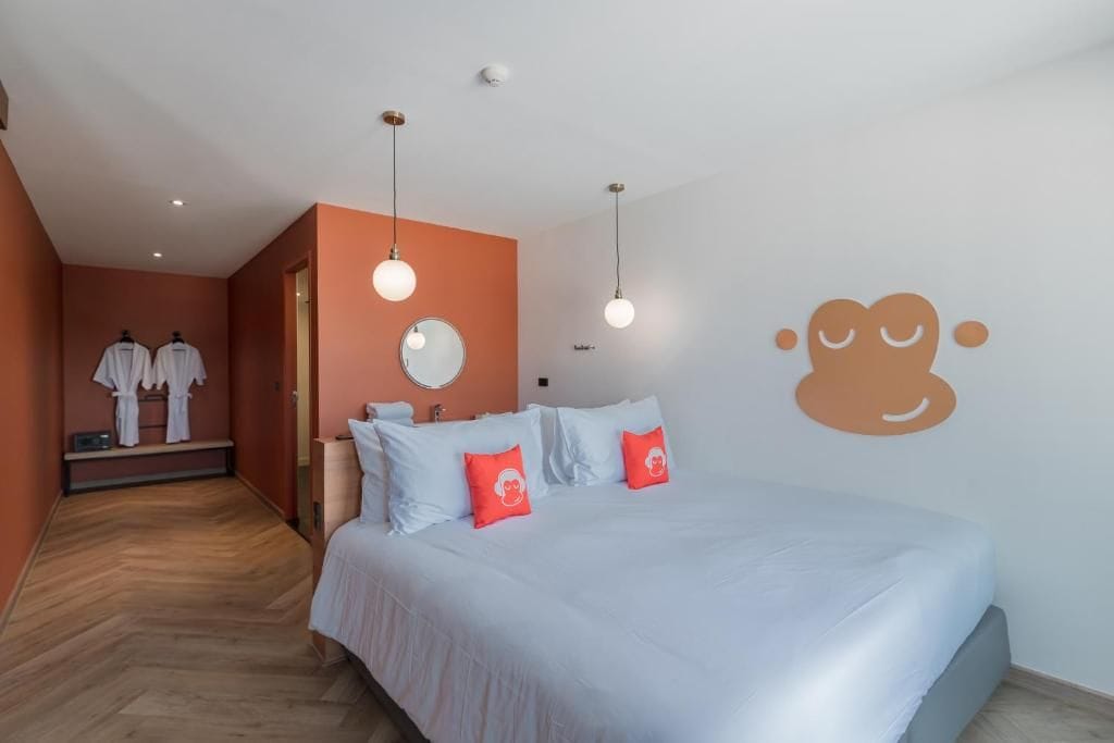 Habitación de hotel con cama, espejo y un muro con diseño de un mono.