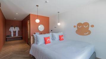 Habitación de hotel con cama, espejo y un muro con diseño de un mono.