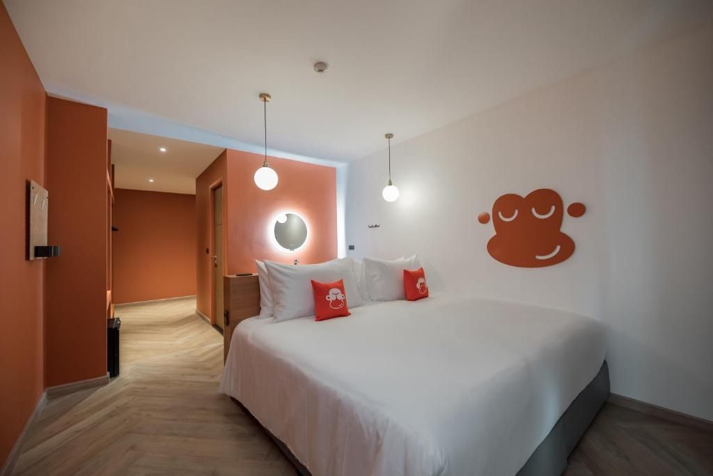 Habitación de hotel con cama, lámpara circular y un adorno de pared.