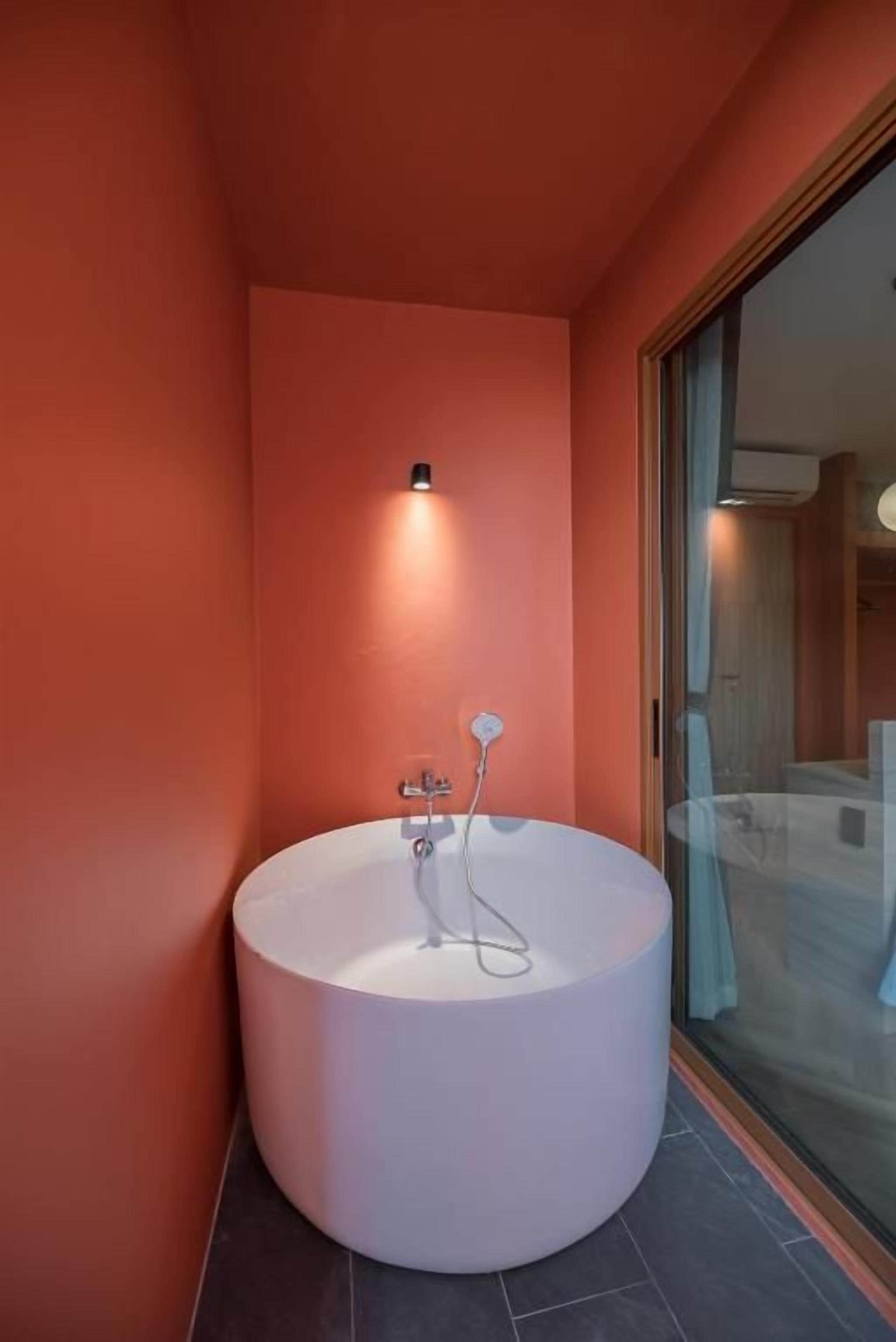 Un baño moderno con una bañera independiente, una lámpara empotrada en la pared y un amplio ventanal que da a la zona de ducha.