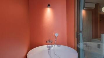 Un baño moderno con una bañera independiente, una lámpara empotrada en la pared y un amplio ventanal que da a la zona de ducha.
