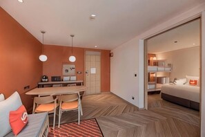 Ein kompaktes Hotelzimmer mit Essbereich, einem Bett und einer separaten Schlafgelegenheit.
