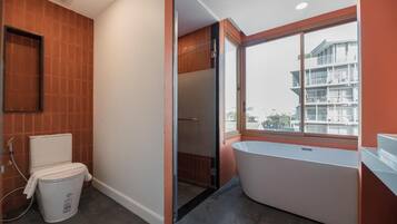 Un baño moderno con inodoro, bañera y ventana con vistas a un edificio.