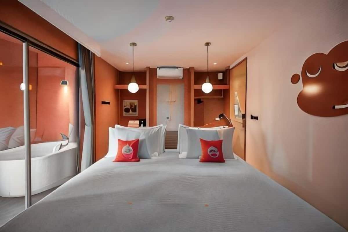 Une chambre d’hôtel moderne dotée d’un grand lit, d’un coin salon avec une table et des chaises, d’une baignoire et d’une grande fenêtre.