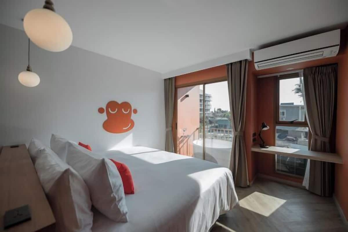 Une chambre d’hôtel équipée d’un lit, d’un bureau, d’un climatiseur et offrant une vue sur l’extérieur.