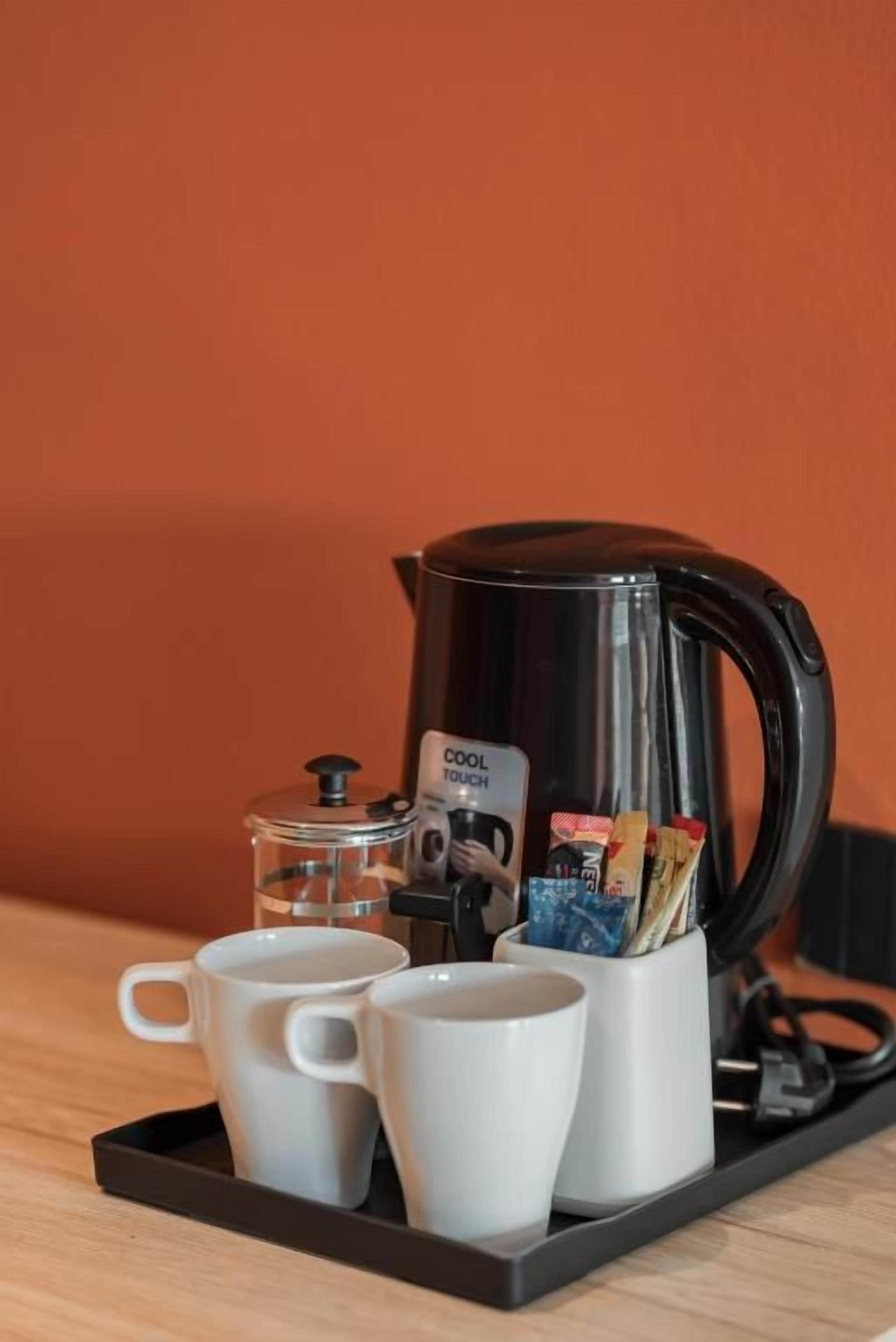 A coffee maker with two white cups on a tray, a coffee pod dispenser, and a coffee grinder.
