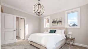 A bedroom with a large bed, a chandelier, a window, and a door. - Luxury Columbus Townhouse with Game Room & Patio (Columbus)