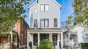 A two-story house with a front porch, a small garden, and a mailbox. - Luxury Columbus Townhouse with Game Room & Patio (Columbus)
