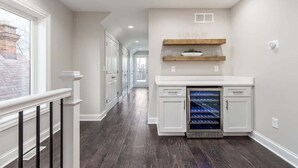 A hallway with a white refrigerator, wooden shelves, and a white countertop. - Luxury Modern Harrison West Home with Rooftop Terrace & Family Amenities (Columbus)
