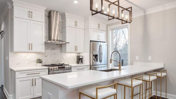 A modern kitchen with white cabinetry, stainless steel appliances, and a central island with bar stools. - Luxury Modern Harrison West Home with Rooftop Terrace & Family Amenities (Columbus)