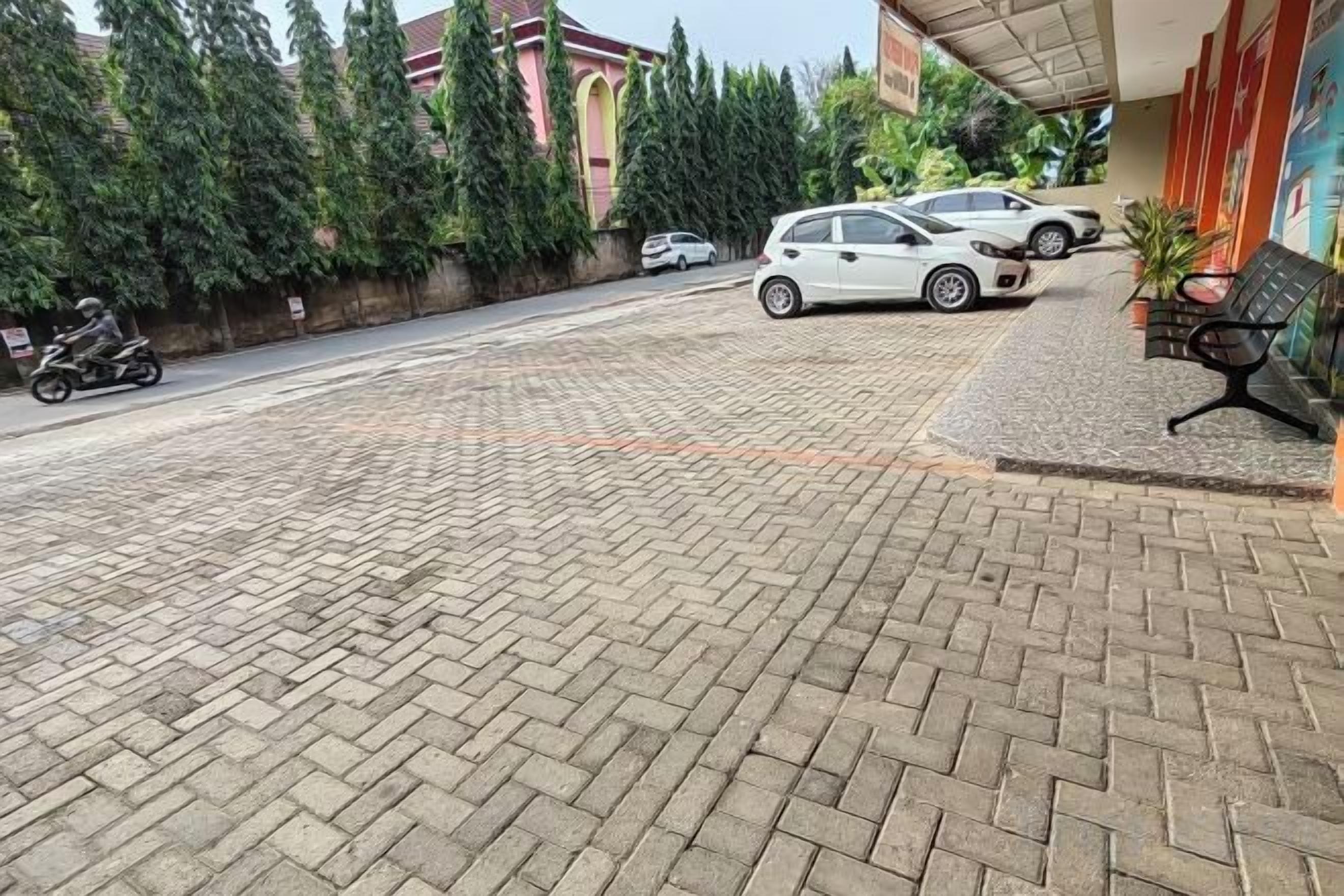 Un camino pavimentado que conduce a un edificio con un coche aparcado y una motocicleta.