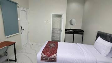 Ein Hotelzimmer mit Bett, Schreibtisch, Stuhl, Spiegel, Tür und Klimaanlage.