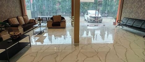 A hotel lobby with a marble floor, sofas, a coffee table, and a view of the street.
