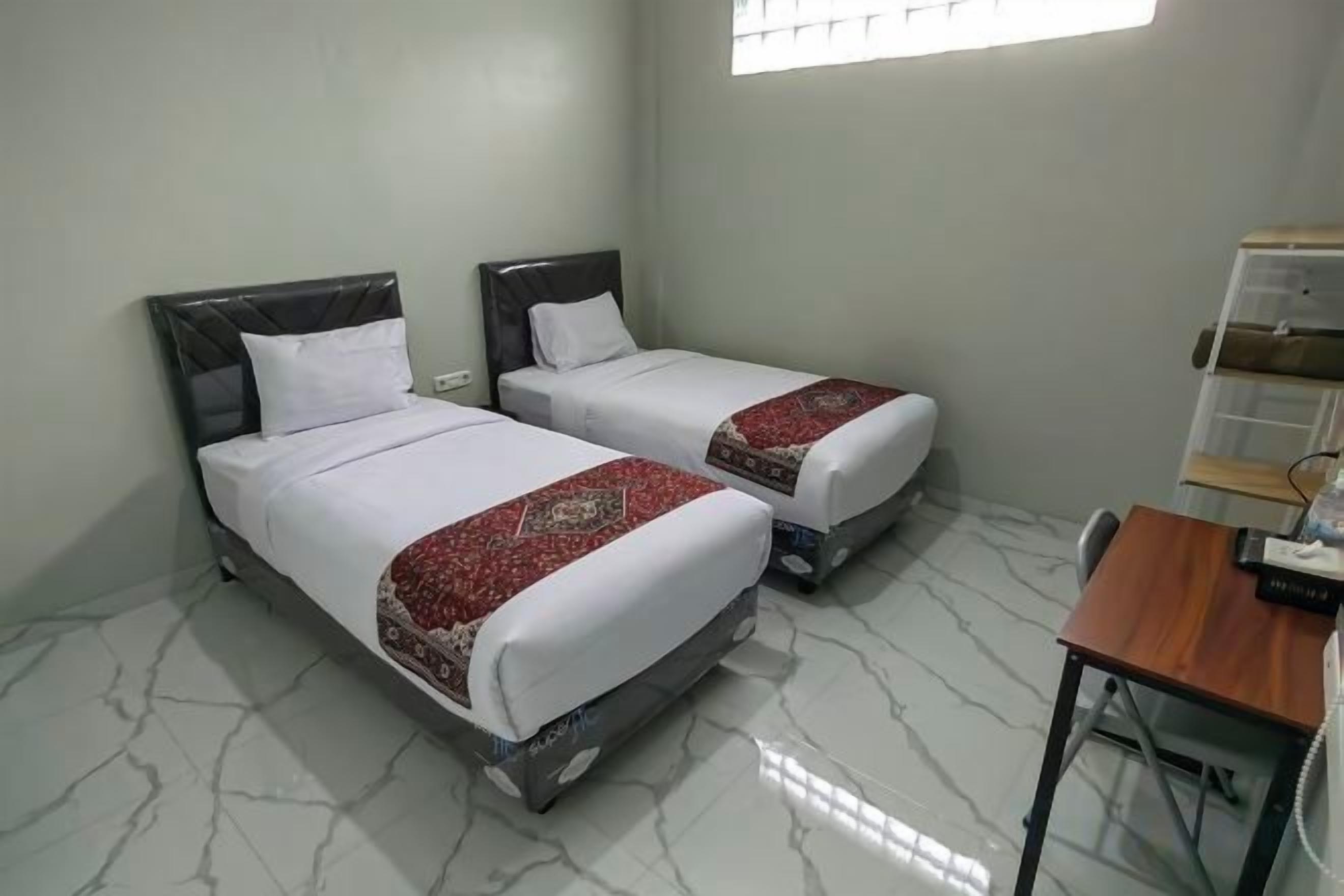 A room with two beds, a desk, and a chair.