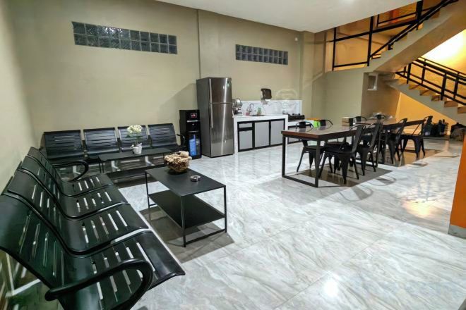A modern kitchen with a refrigerator, stove, and dining area with chairs and a table.