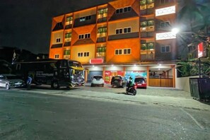 A multi-story building with a parking area in front. - Joy Hotel (Rajabasa)