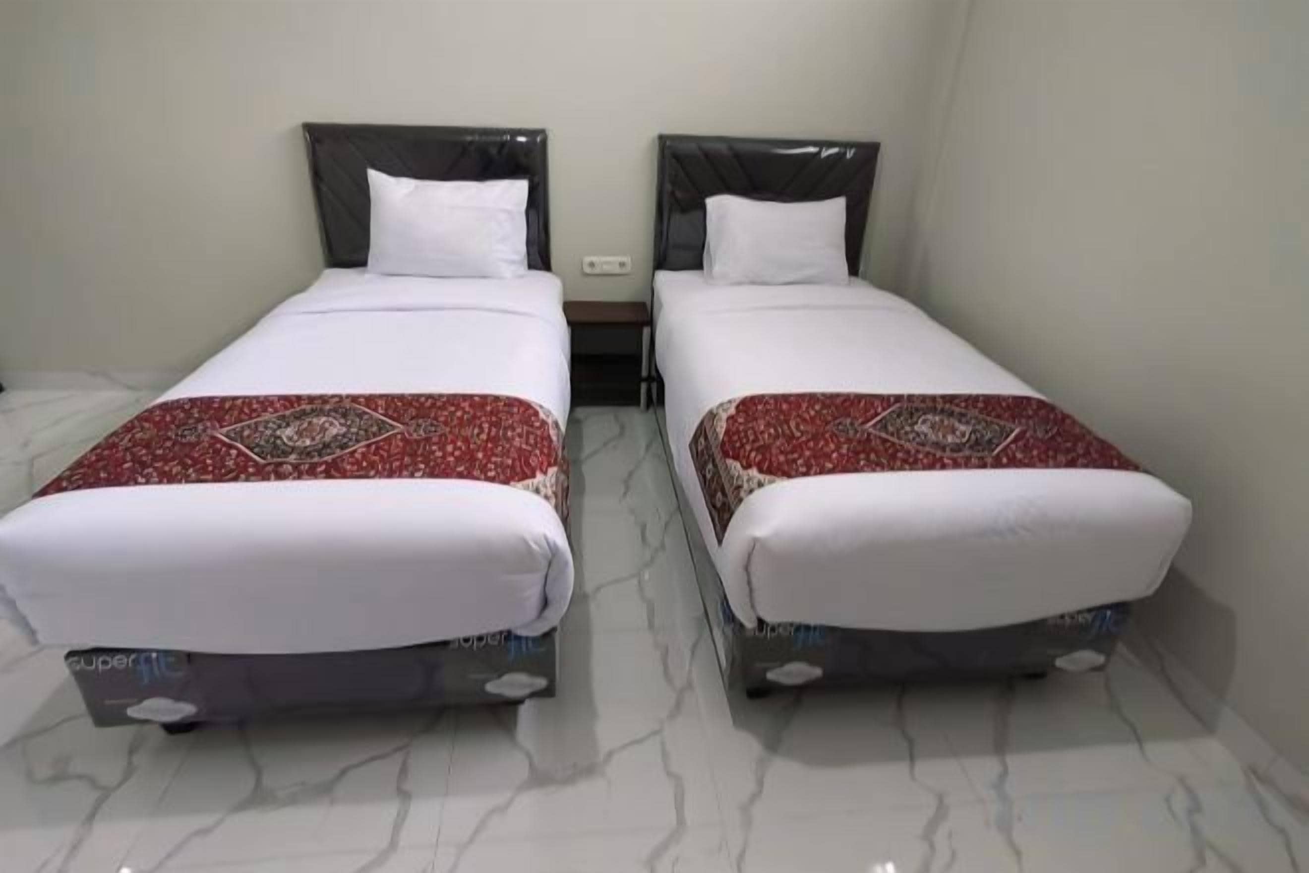 Two single beds with headboards, white bedding, and a red patterned throw.
