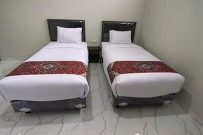 Two single beds with headboards, white bedding, and a red patterned throw. - Joy Hotel (Rajabasa)