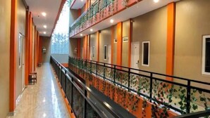 Pasillo de hotel con barandilla de vidrio, puertas y piso de mármol.
