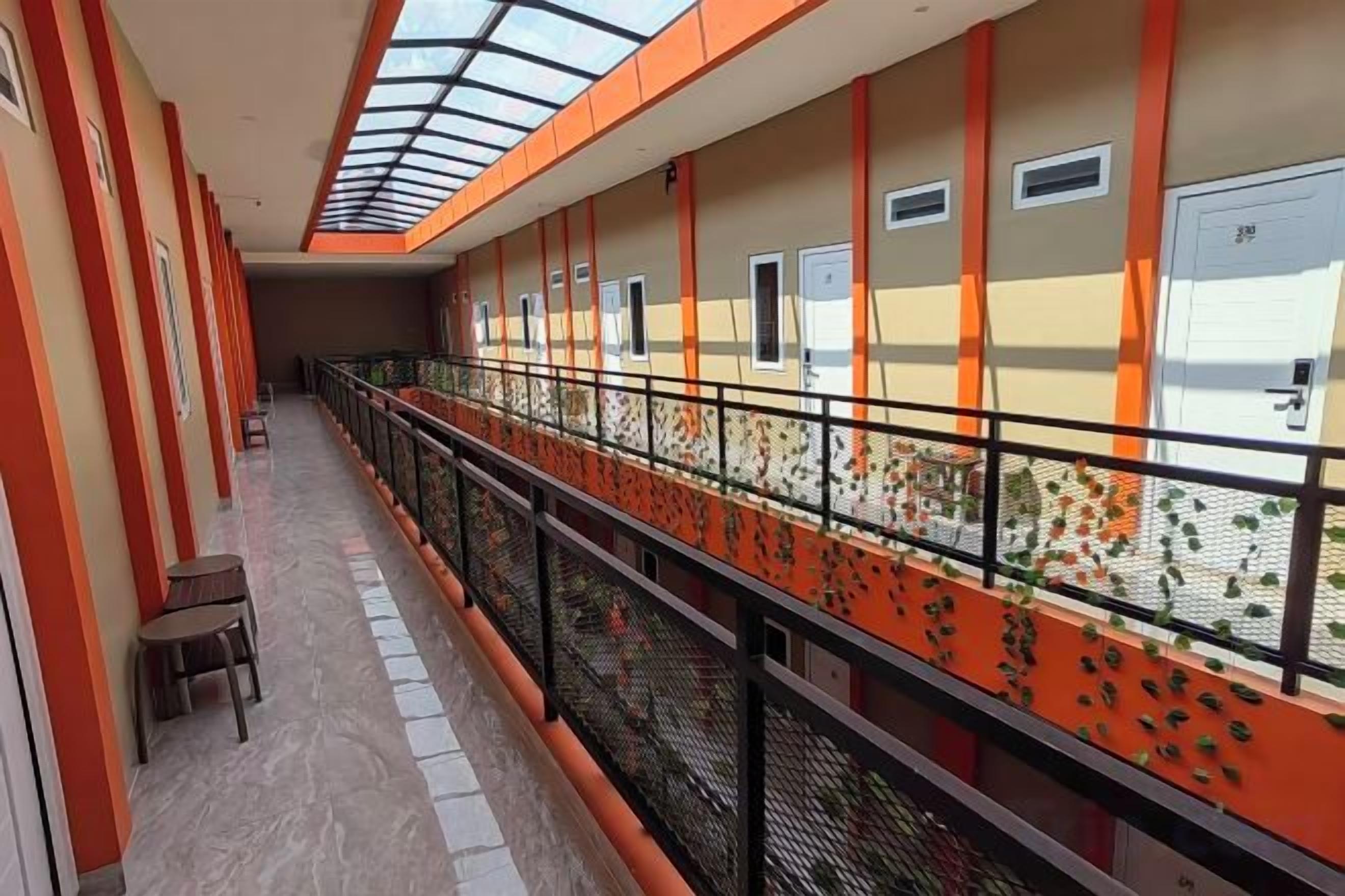 A corridor with a glass ceiling, orange walls, and a metal railing.