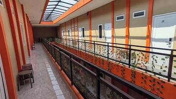 A corridor with a glass ceiling, orange walls, and a metal railing.