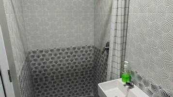 Ein Badezimmer mit gemusterten Fliesen, einem weißen Waschbecken und einer grünen Seifenflasche.