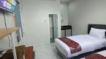 A hotel room with a bed, a TV, a desk, and a chair.