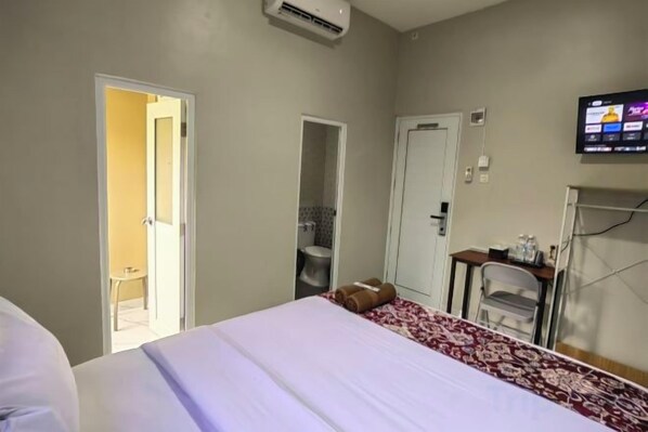 Une chambre d’hôtel avec un lit, une télévision, un bureau et une chaise.