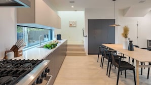 A modern kitchen with a gas stove, a window, and a dining area with a table and chairs. - Modern East Austin Home w/ Pool, Near Downtown & Lady Bird Lake Casa 1803 by Avantstay (Austin)