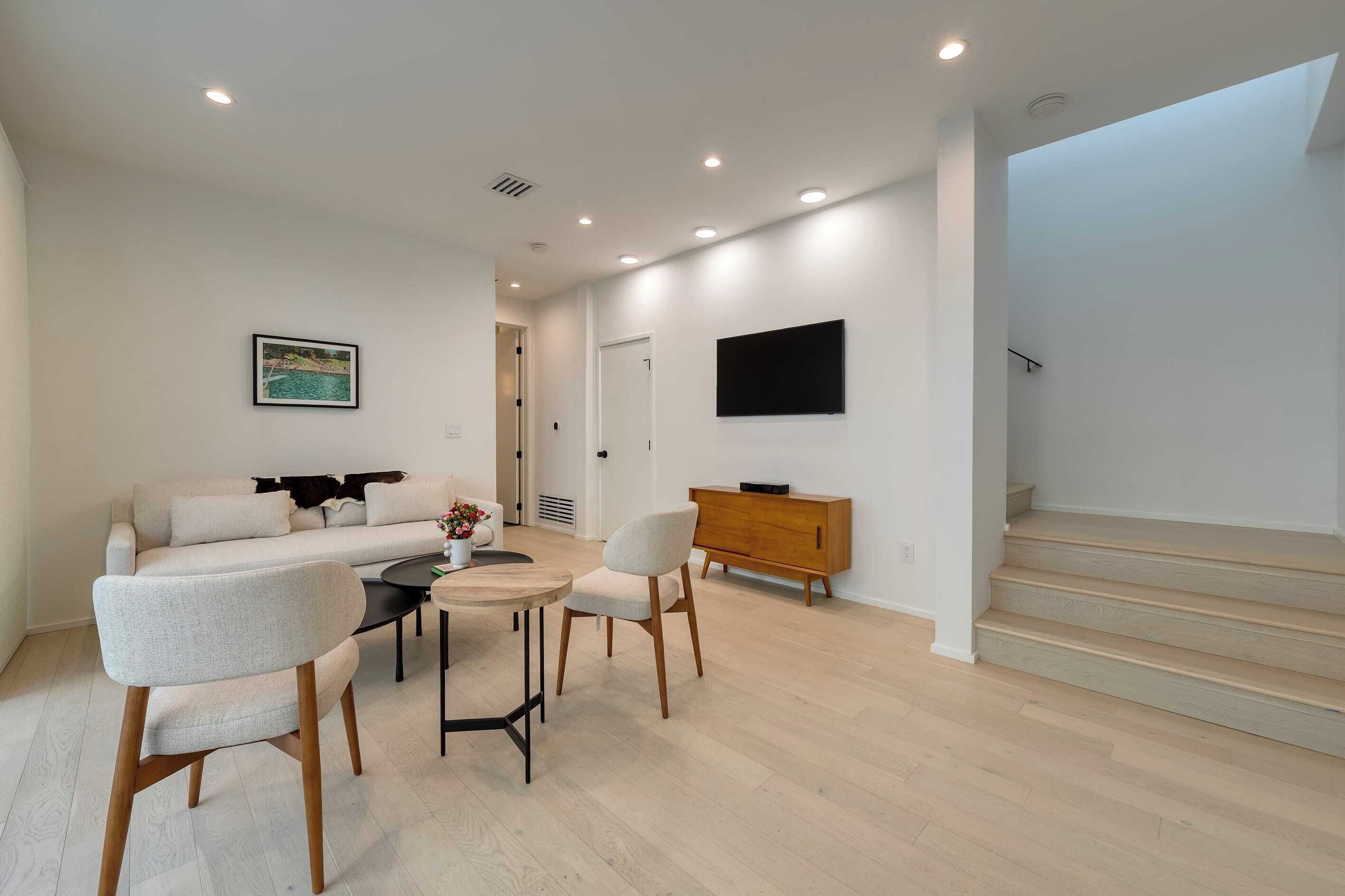 A modern living room with a sofa, chairs, a coffee table, and a TV mounted on the wall.