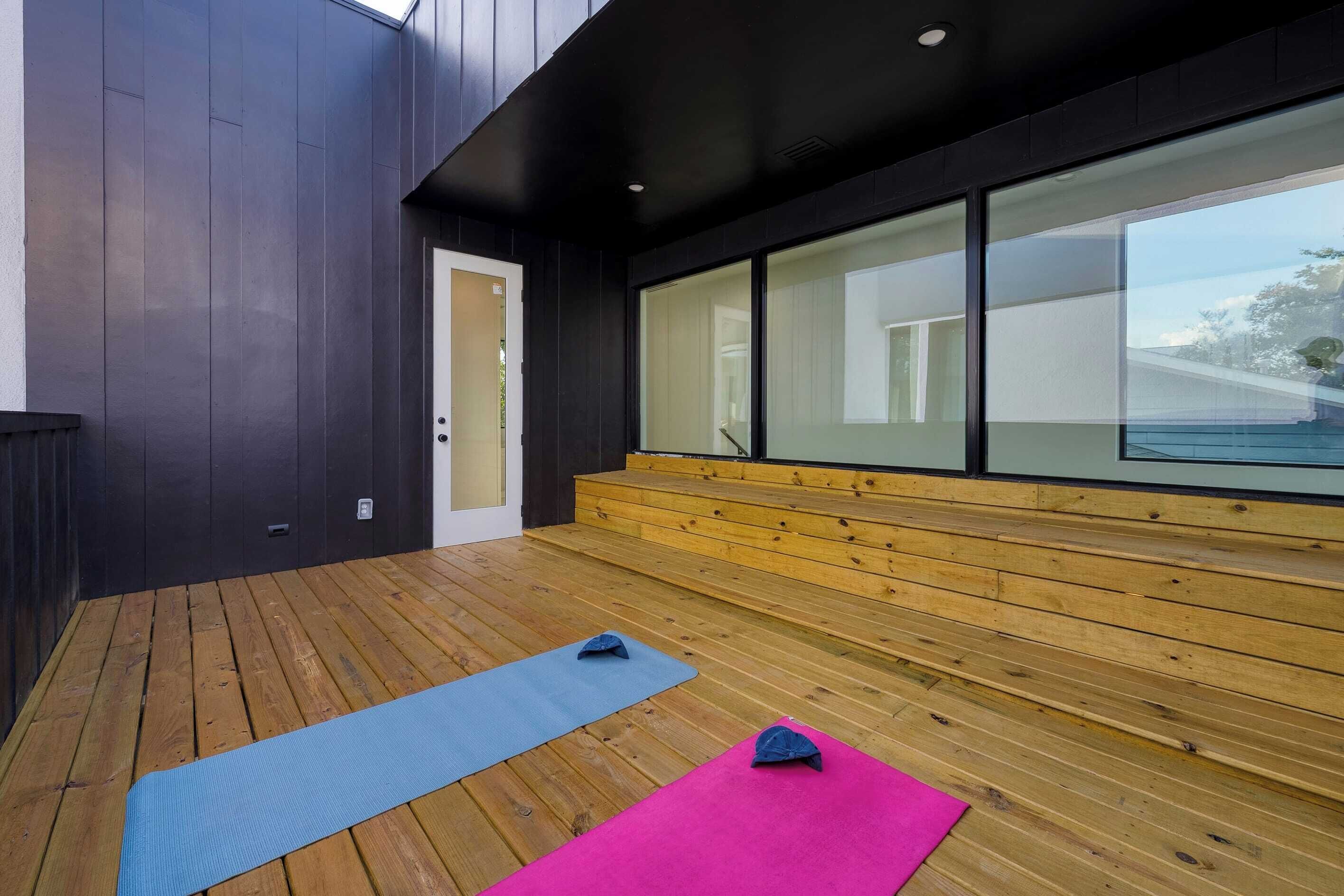 An outdoor wooden deck with exercise mats and a bench.