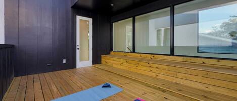 An outdoor wooden deck with exercise mats and a bench.