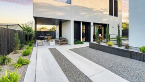 A modern house with a patio area featuring a seating arrangement and a small garden. - Modern East Austin Home w/ Pool, Near Downtown & Lady Bird Lake Casa 1803 by Avantstay (Austin)