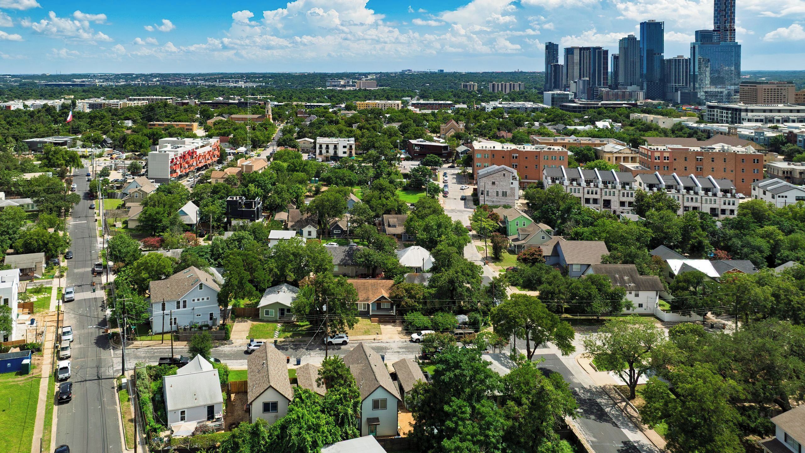 A residential area with houses, streets, and a distant city skyline.