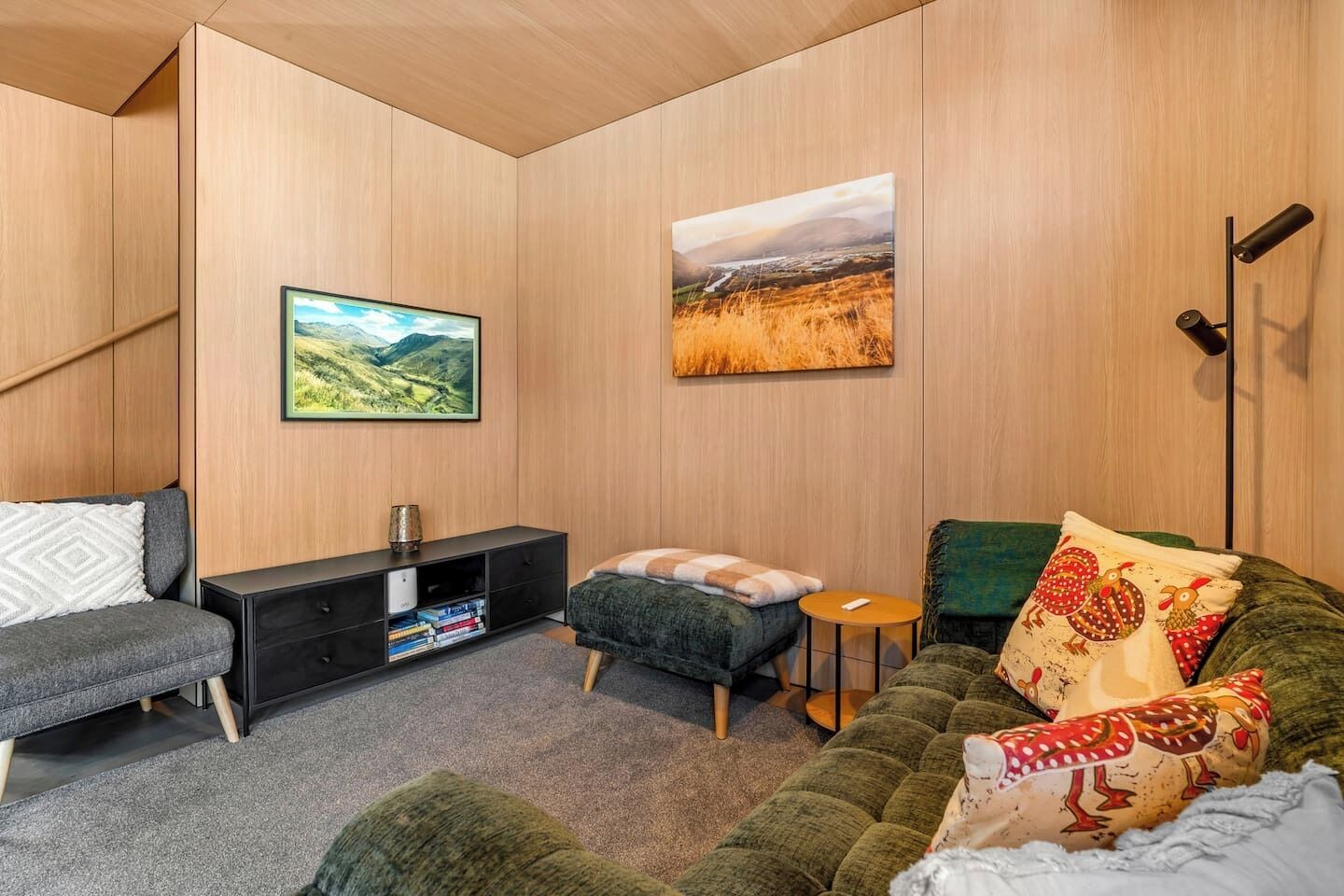 Un salon moderne avec un canapé, une petite table, un meuble et deux tableaux accrochés au mur.