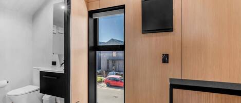A modern bathroom with a toilet, sink, and a glass door leading outside.