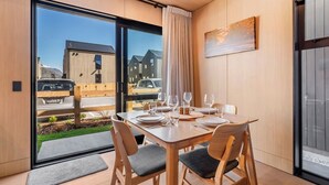 Ein Essbereich mit einem Tisch für vier Personen, großen Fenstern und Blick auf Gebäude.