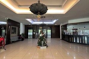 Un vestíbul ampli amb un arbre de Nadal, ascensors i una taquilla d'informació.
