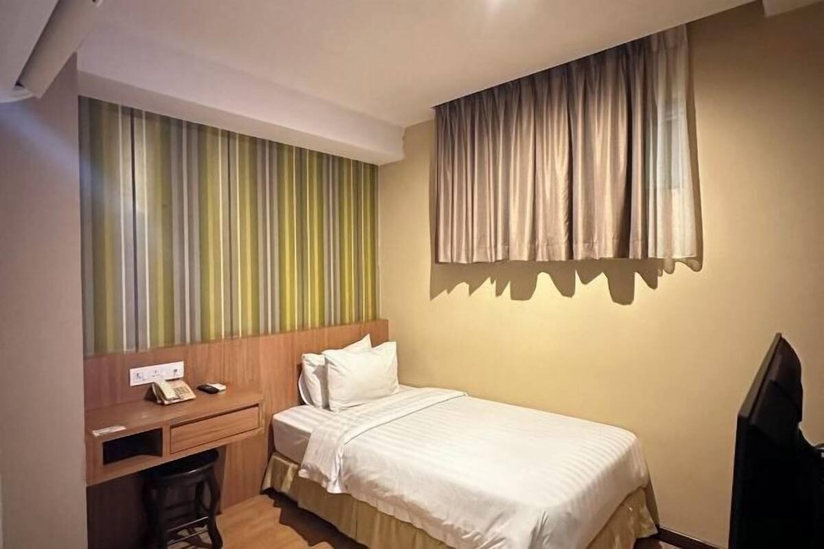A hotel room with a bed, a desk with a telephone, and a television.