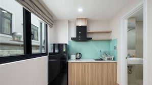 A compact kitchen with a black refrigerator, a microwave, a wooden countertop, and a black range hood. - Siris Mia Residence - Self Check In (Ho Chi Minh City)