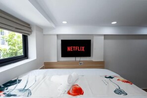 A hotel room with a bed, a window, and a wall-mounted television displaying the Netflix logo. - Siris Mia Residence - Self Check In (Ho Chi Minh City)