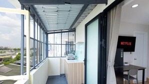 A balcony with a view of the city, a desk with a chair, and a TV screen displaying "NETFLIX". - Siris Mia Residence - Self Check In (Ho Chi Minh City)