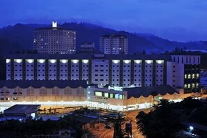 Un hotel de varios pisos con un patio central, rodeado de edificios y un paisaje montañoso al fondo.