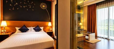 Habitación de hotel con una cama grande, lámparas de noche, ventilador de techo, un ventanal con cortinas y vistas al exterior.