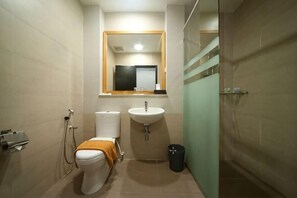 Un baño con inodoro, lavabo, espejo y zona de ducha.