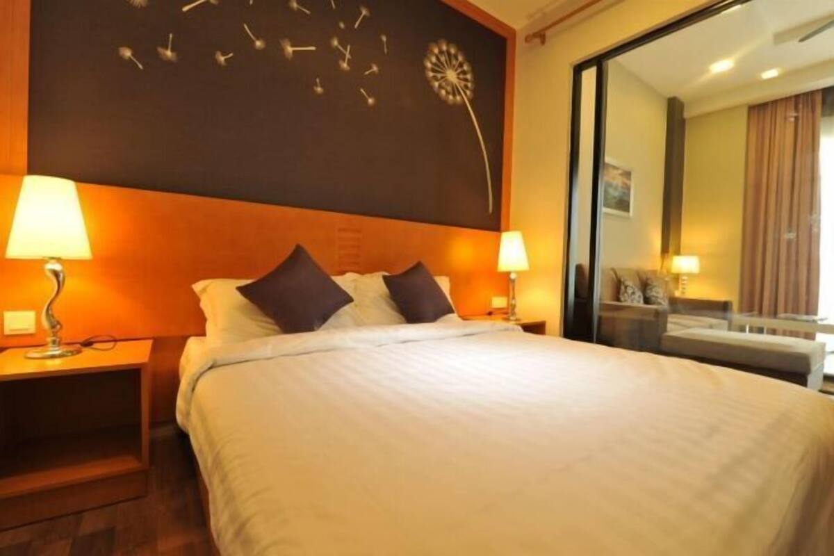 Een hotelkamer met een groot bed, twee nachtkastjes met lampen, een wandklok en een spiegel.